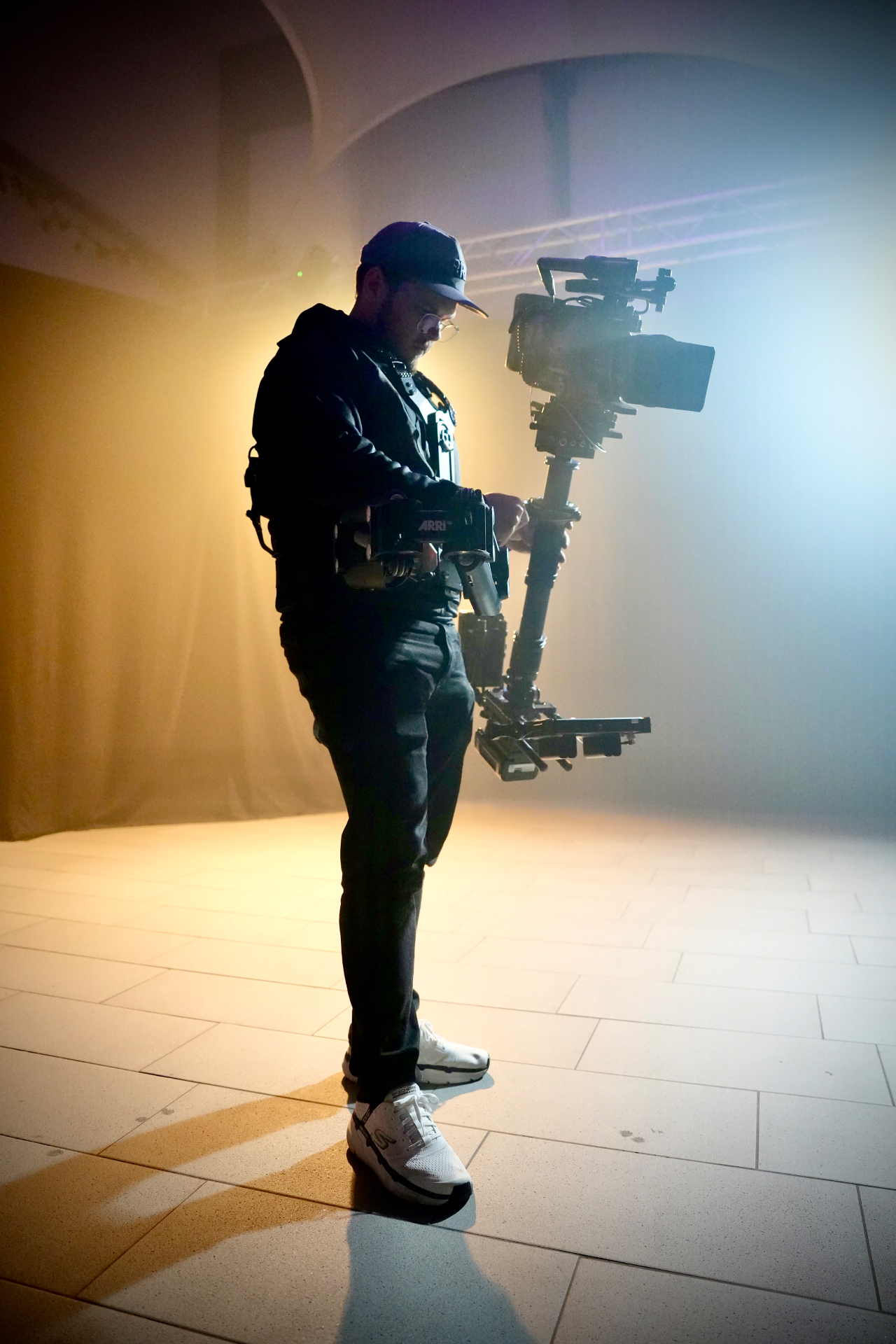 Silhouette of a camera operator with a steadicam rig in hazy stage light