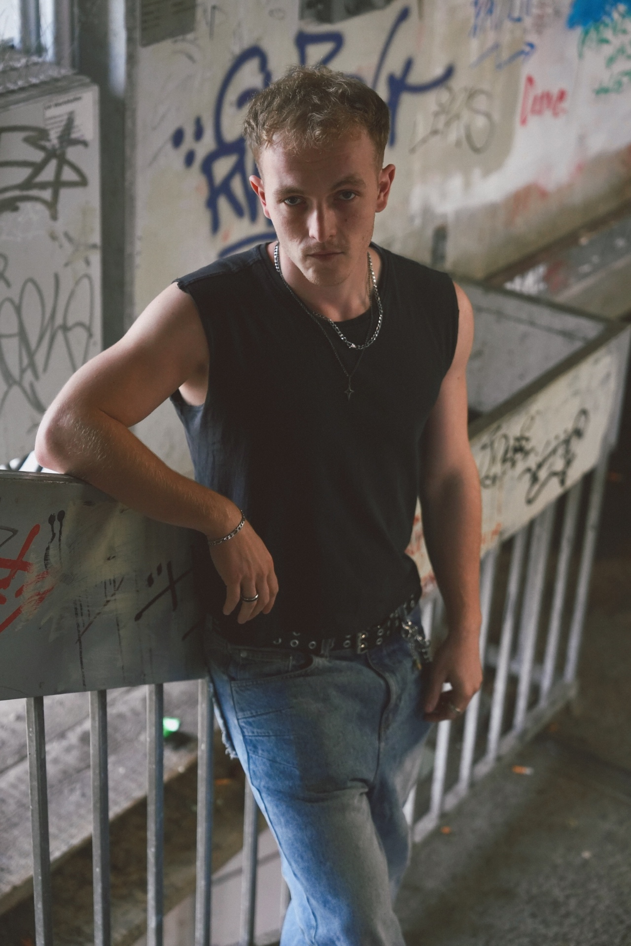 Portrait of a man leaning on a railing in a graffiti-covered stairwell