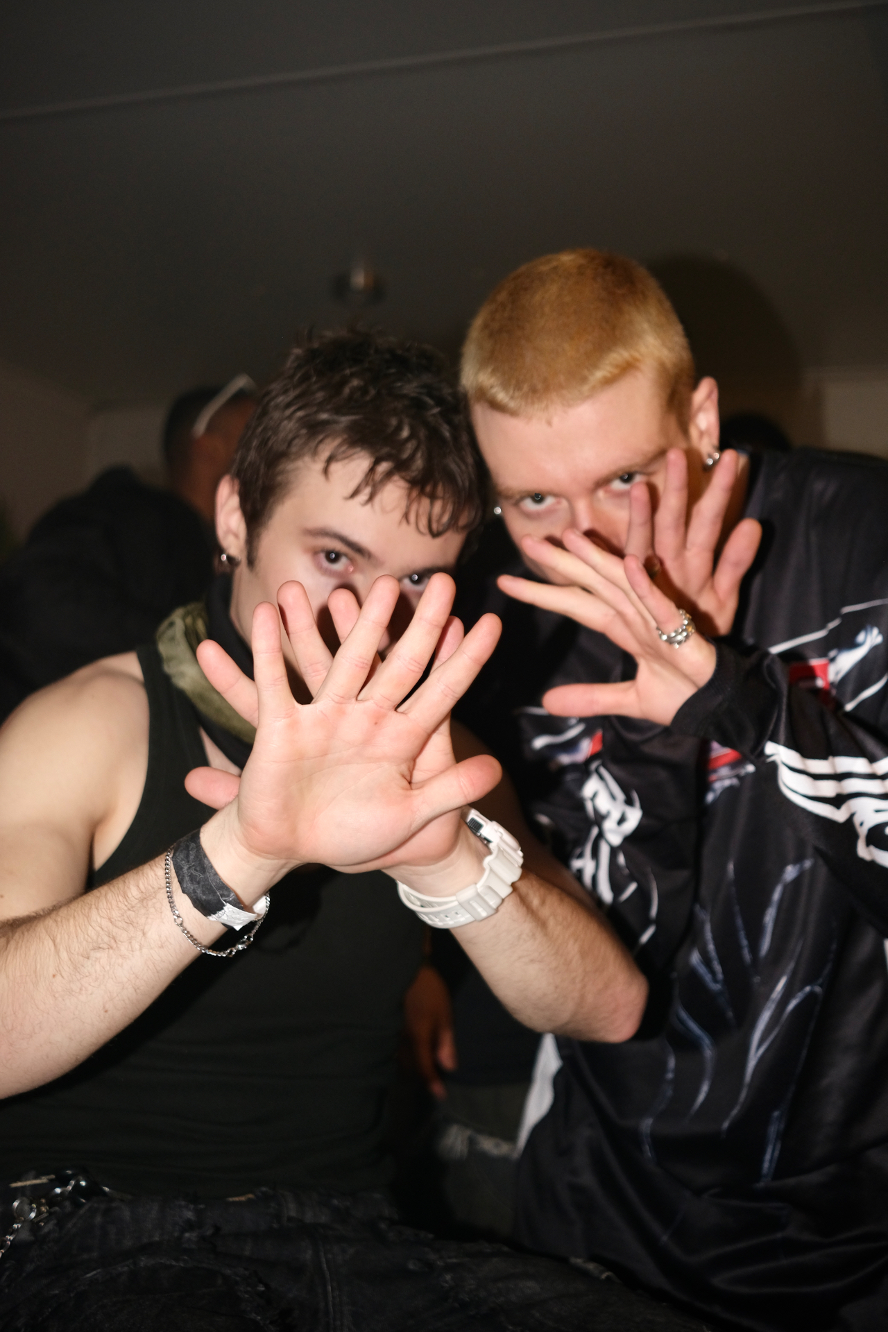 Two people at a club with hands raised toward the camera
