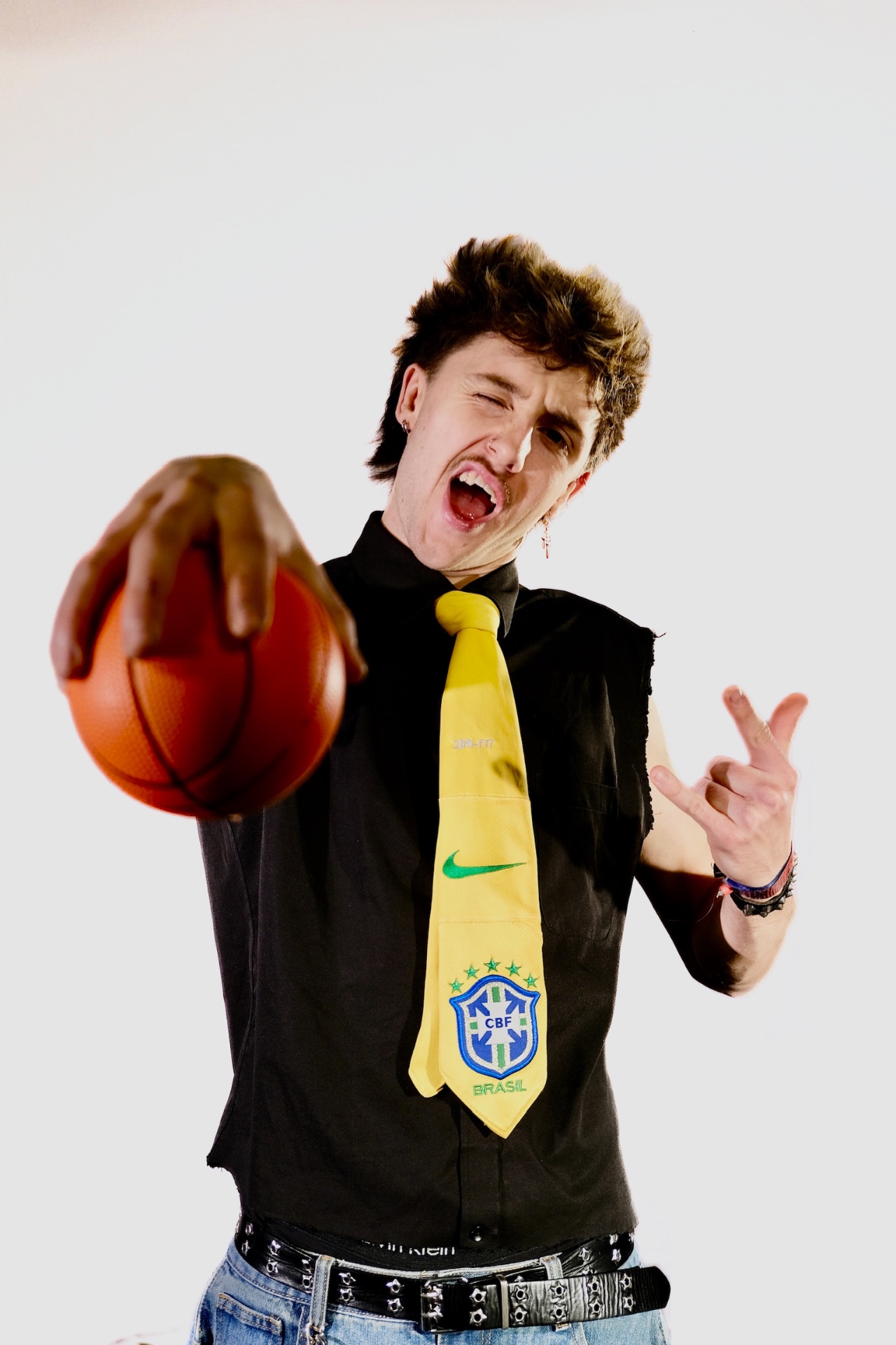 Studio portrait of a man shouting while holding a basketball toward the camera