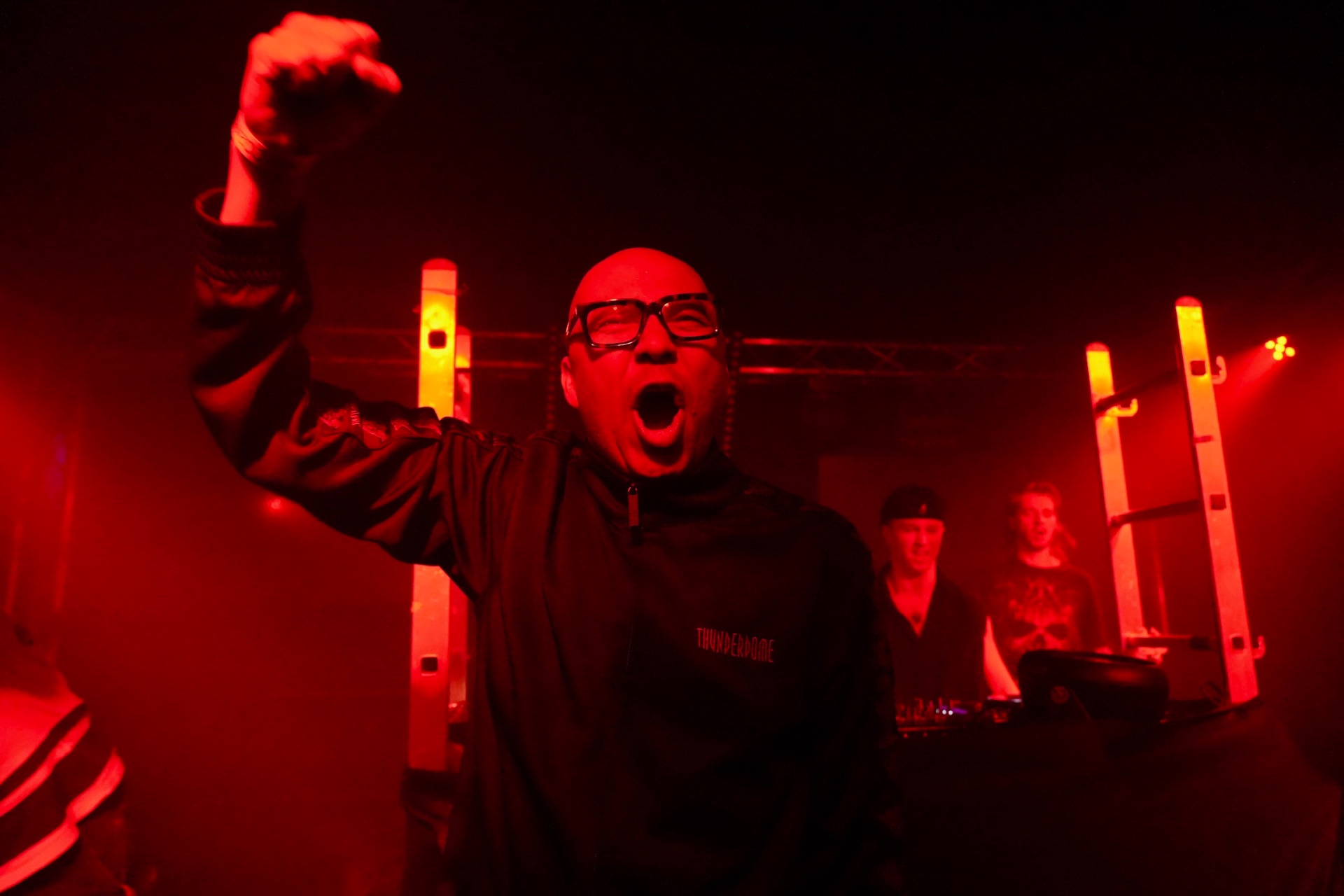Man cheering with a raised fist under deep red club lighting